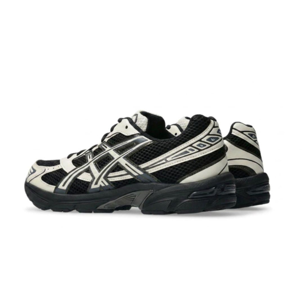 A pair of ASICS athletic sneakers in black and off-white, shown from a side profile view against a plain white background.
