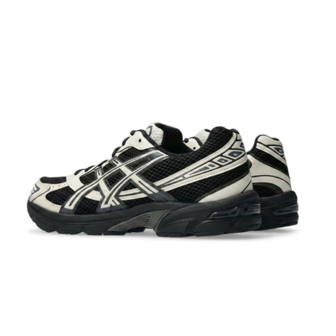 A pair of ASICS athletic sneakers in black and off-white, shown from a side profile view against a plain white background.