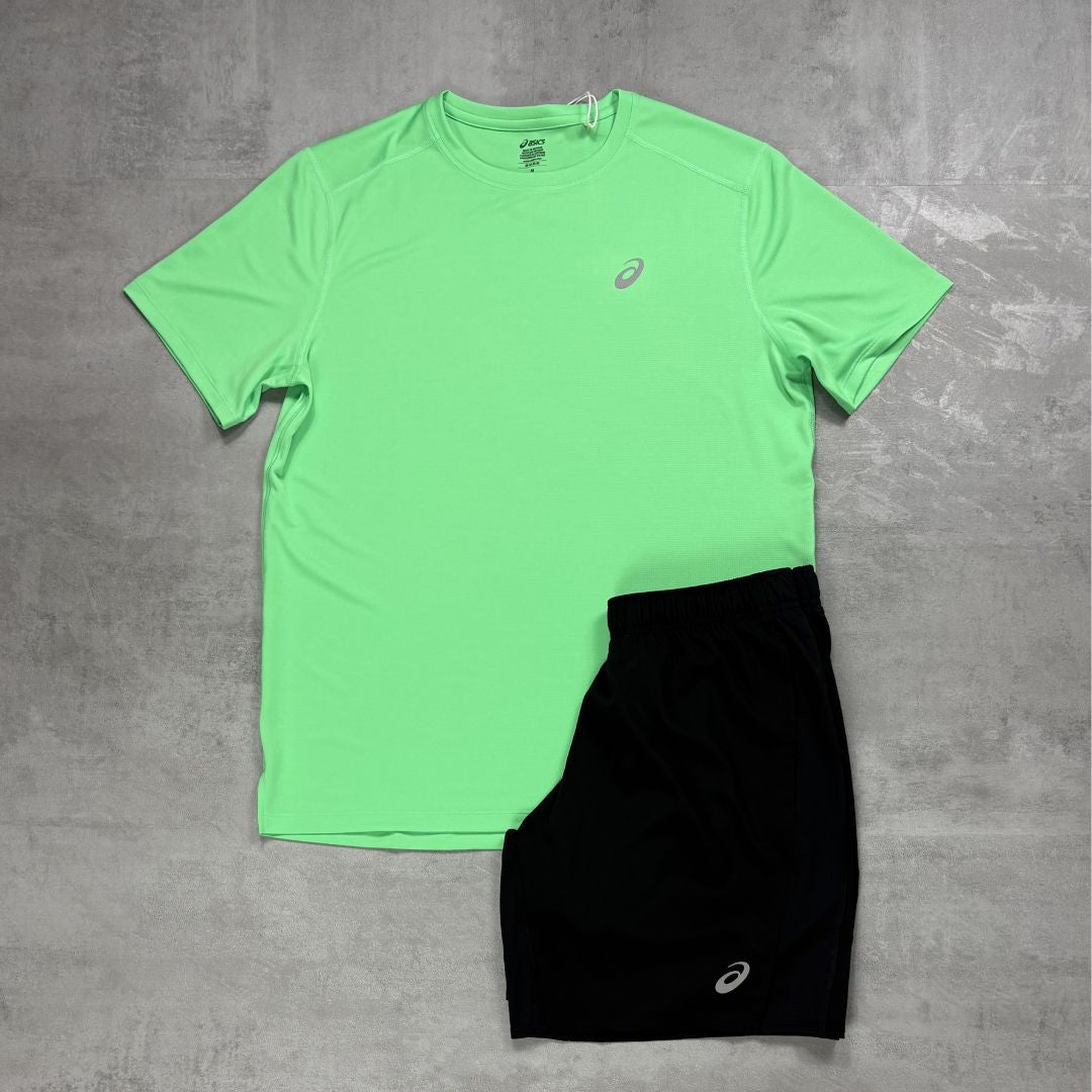 Green t-shirt and black shorts with a Asics logo on a gray surface