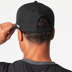 Agaru 'Carbon Black' SRG Cap for men, back view on model showing the adjustable snap clasp closure on the black structured cap