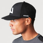 Agaru 'Carbon Black' SRG Cap for men, side view on model showing the Agaru wordmark on the side panel and structured cotton crown of the black cap