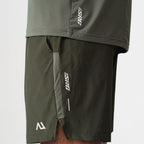 Agaru 'Deep Olive' SRG Shorts for men, close-up of the zipped side pocket, SRG logo print and Agaru branding on the dark olive woven shorts