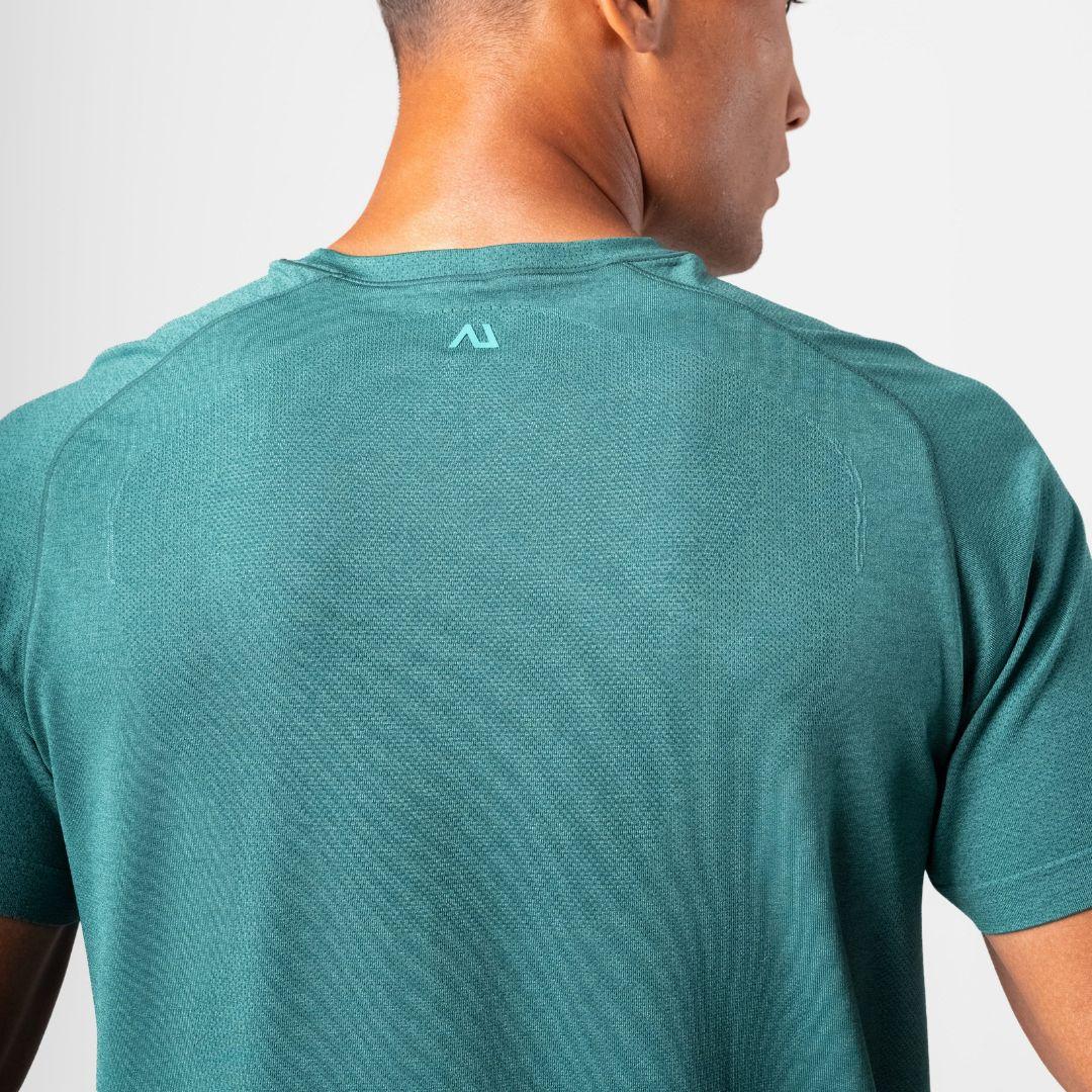 A close-up back view of a man wearing a teal athletic t-shirt, showing the textured fabric and a small light teal logo on the upper back.
