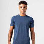 A man wearing a heathered blue crewneck t-shirt with a small light blue Agaru sports logo on the left chest, photographed against a light gray studio background.