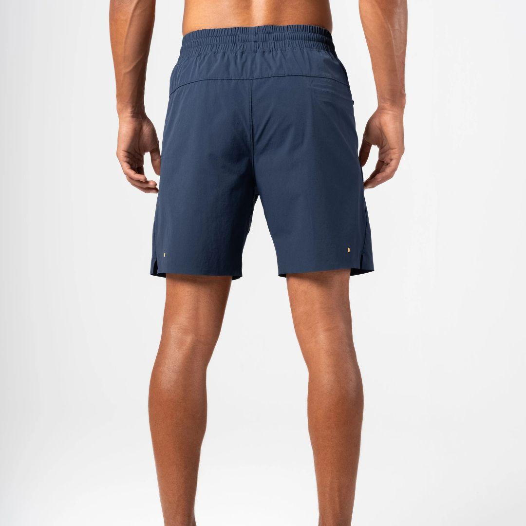 Rear view of a man wearing navy blue athletic shorts against a clean white studio background.