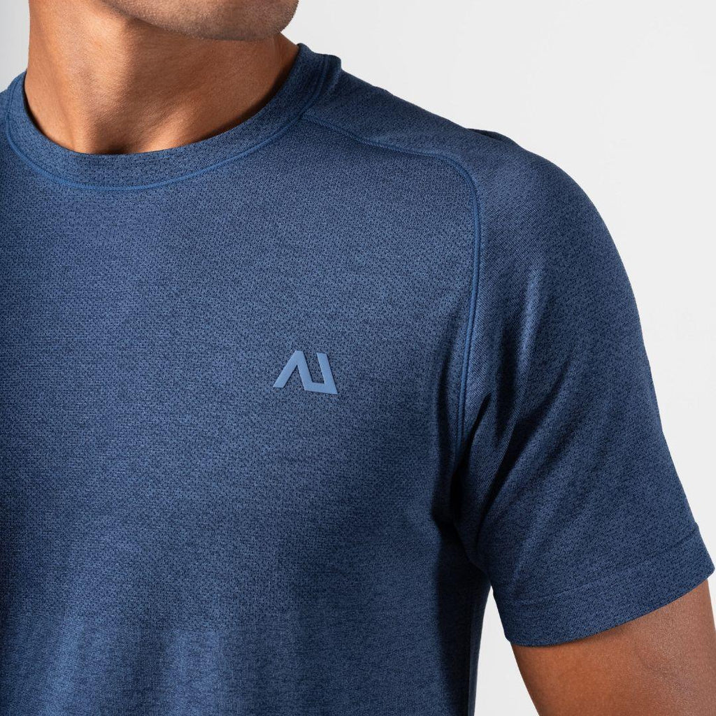 Close-up of a man wearing a heathered blue short-sleeve athletic t-shirt with a light blue geometric Agaru Sports logo on the left chest, set against a plain light gray background.