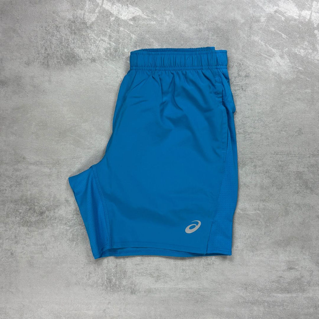 Asics Blue athletic shorts with a logo on a gray concrete surface