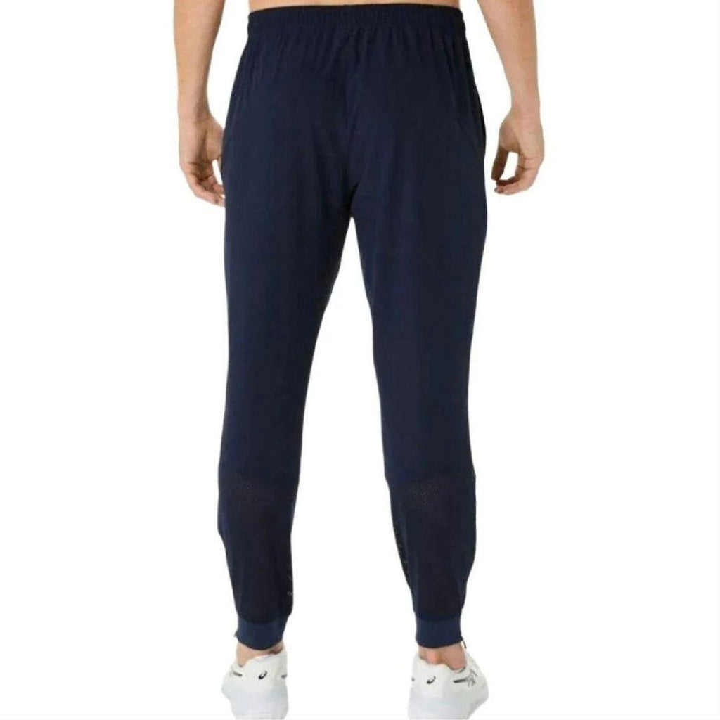 Asics Navy Core Woven Pant for men, back view on model showing the tapered fit, part of the Aqua Core Windrunner and Pant Tracksuit