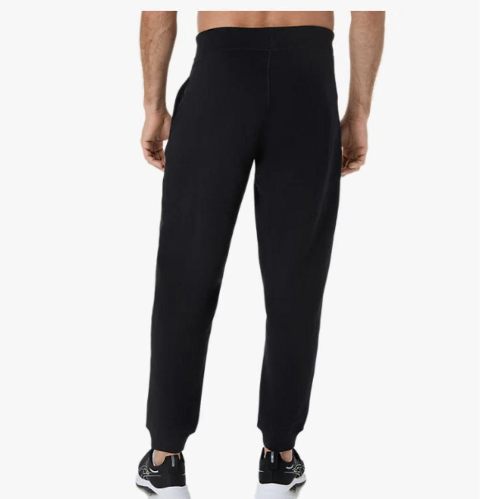 Asics Black Jogger for men, back view on model of black joggers with wide elasticated waistband, side pockets and ribbed ankle cuffs, part of the Asics Black Hoodie and Jogger Tracksuit