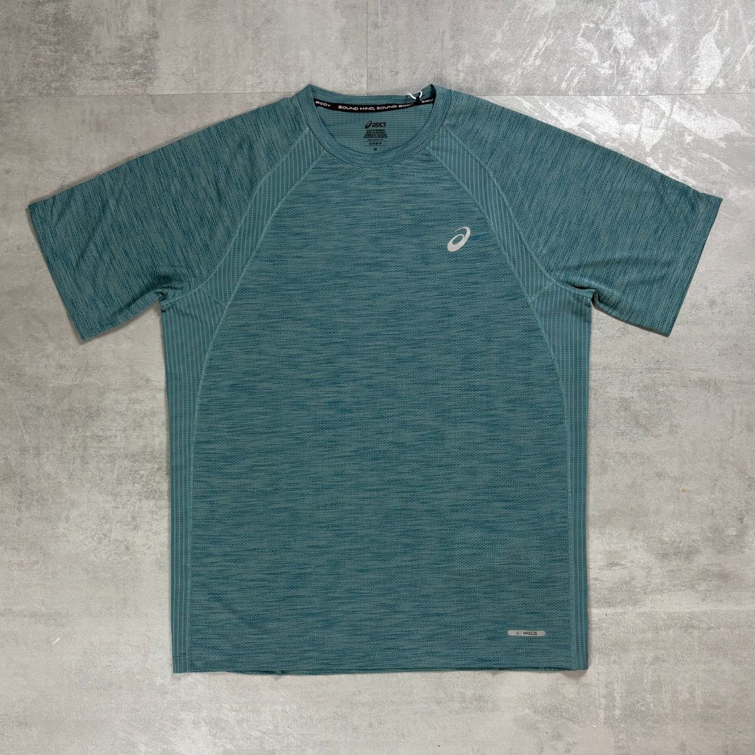 A teal heathered short-sleeve athletic t-shirt with a small white Asics logo on the left chest, laid flat on a gray textured surface.