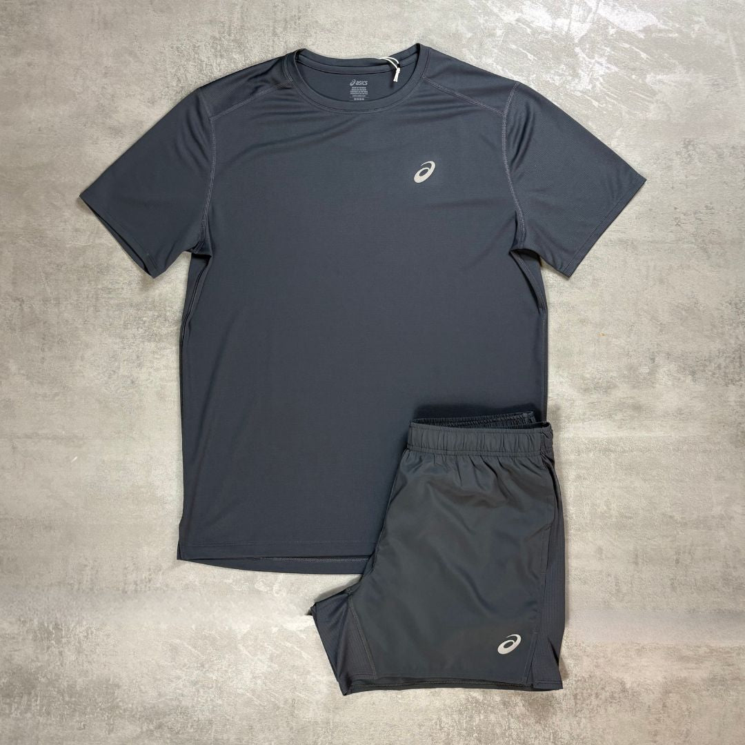 an Asics grey core t-shirt and shorts set flatlayed on a grey concrete background