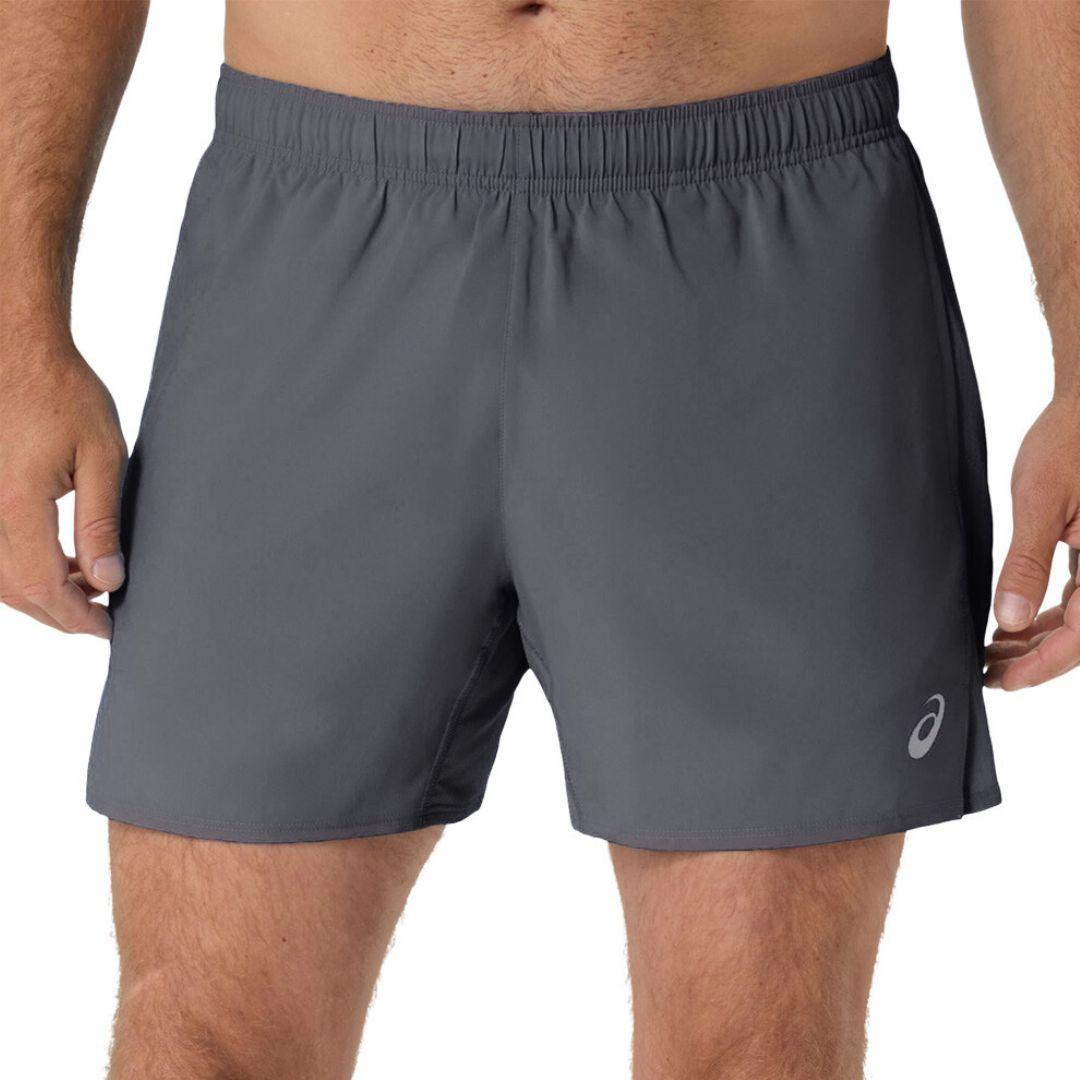 A close-up of a person wearing dark gray athletic shorts with an elastic waistband and a small white Asics logo near the lower right leg, shown against a plain white background.