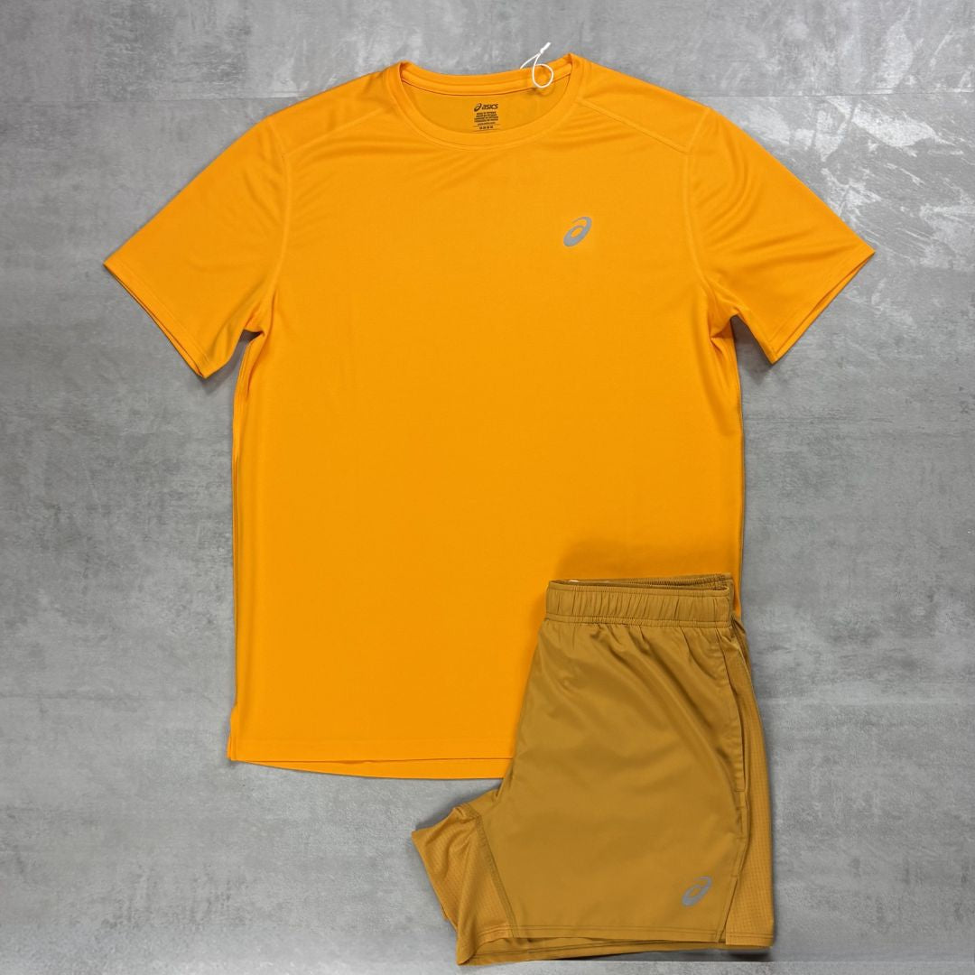 Asics Orange t-shirt and shorts set on a gray concrete surface