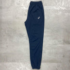 Asics Navy Core Woven Pant for men, flat lay side view of navy training trouser with side pockets, ankle zips and Asics logo