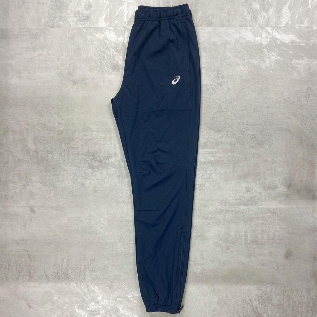 Asics Navy Core Woven Pant for men, flat lay side view of navy training trouser with side pockets, ankle zips and Asics logo