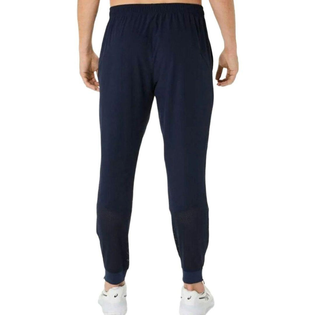Asics Navy Core Woven Pant for men, back view on model showing the tapered fit and ankle zips of the navy training trouser
