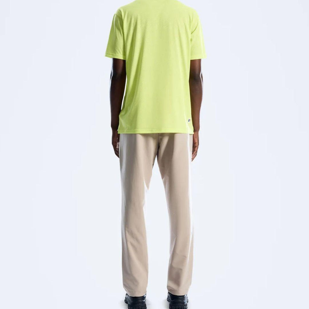 A man viewed from the back wearing a Berghaus bright lime green t-shirt and beige trousers, standing against a plain white studio background.