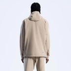 A person shown from the back wearing a Berghaus light beige hooded jacket and matching beige pants against a plain light gray studio background.