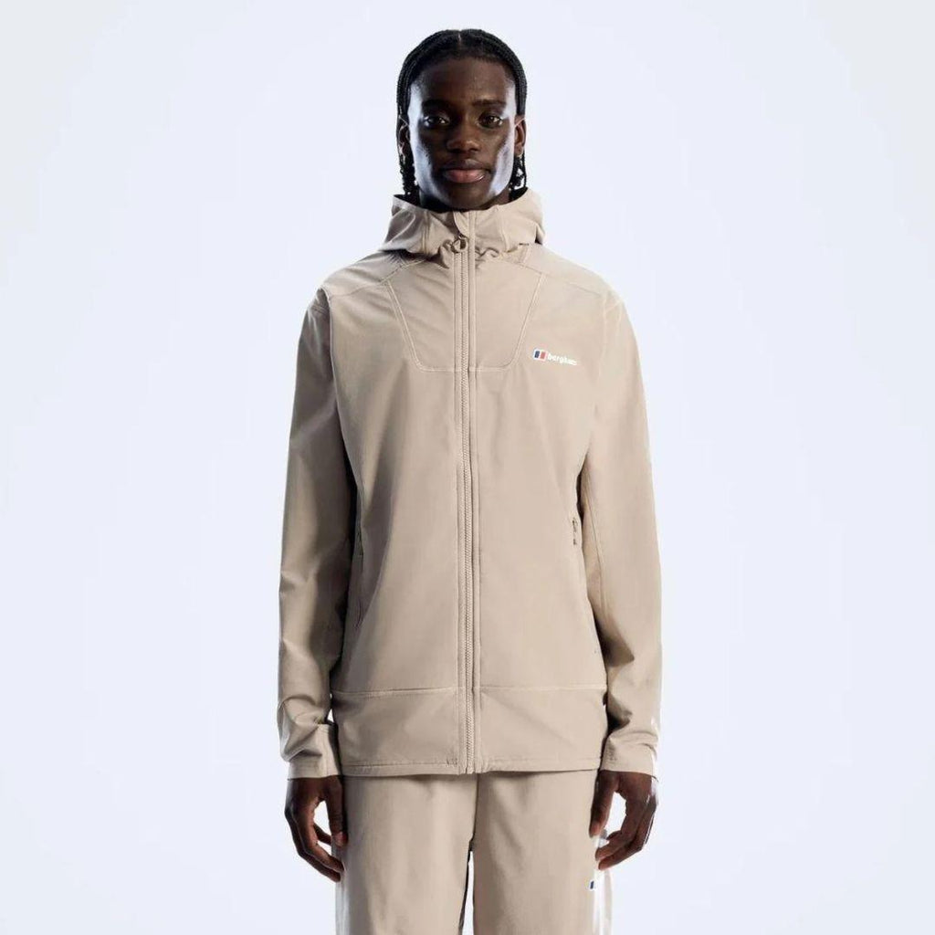 A model wearing a beige hooded zip-up jacket and matching beige pants against a clean white studio background. The jacket features a small red, white, and blue Berghaus logo on the left chest.