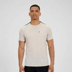 A man wearing a Berghaus light beige short-sleeve athletic t-shirt with black shoulder stripes and a small red and blue logo on the chest, photographed against a light gray studio background.