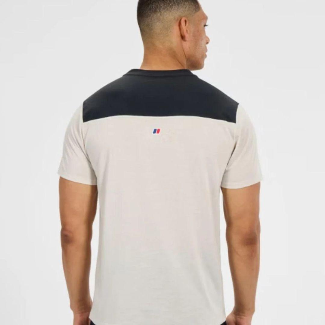 A man viewed from the back wearing a short-sleeve crew-neck t-shirt with a dark navy shoulder yoke and a small red, white, and blue Berghaus logo on the upper back.