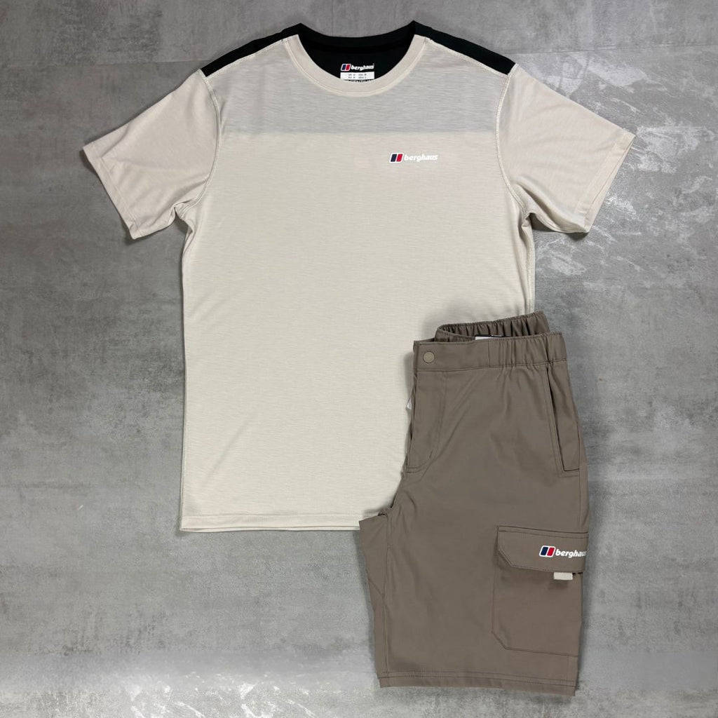 A short-sleeve athletic t-shirt and matching cargo shorts set from Berghaus, laid flat on a gray concrete-textured background. The t-shirt is off-white with a black yoke and shoulder panels, and features a small berghaus logo on the chest.