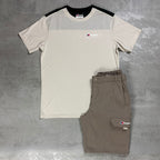 A short-sleeve athletic t-shirt and matching cargo shorts set from Berghaus, laid flat on a gray concrete-textured background. The t-shirt is off-white with a black yoke and shoulder panels, and features a small berghaus logo on the chest.
