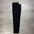 Berghaus Black Everyday Cargo Pant for men, flat lay of black relaxed-fit cargo trousers on a grey concrete surface showing the flap thigh pocket with Berghaus logo label and straight leg
