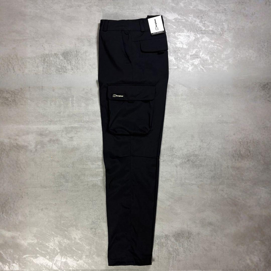 Berghaus Black Everyday Cargo Pant for men, flat lay of black relaxed-fit cargo trousers on a grey concrete surface showing the flap thigh pocket with Berghaus logo label and straight leg
