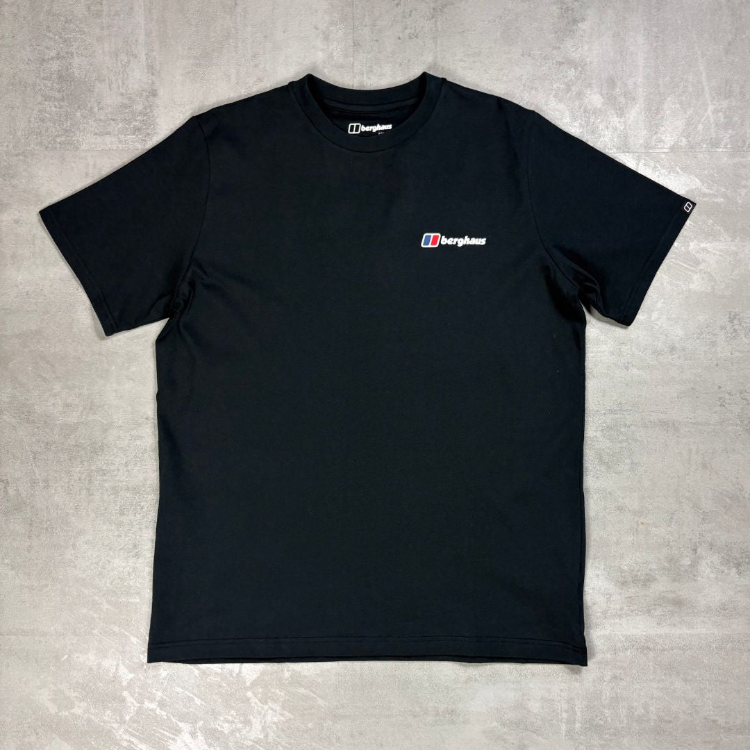 A black short-sleeve crewneck t-shirt with a small Berghaus logo printed on the left chest, laid flat on a textured gray concrete background.
