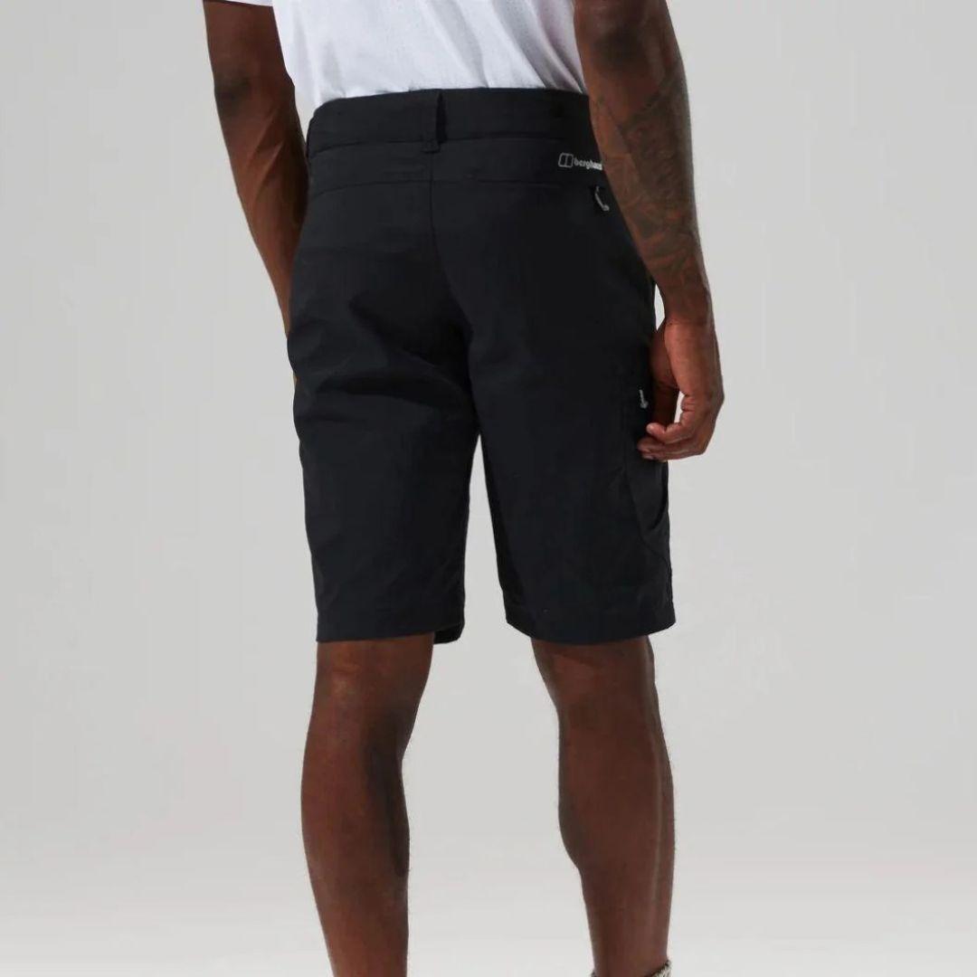 A man wearing black outdoor cargo shorts, shown from a rear three-quarter angle against a light gray studio background.