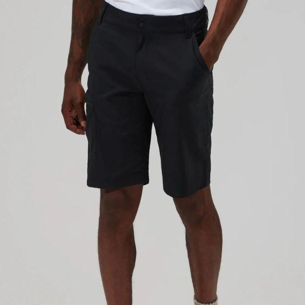A person wearing dark charcoal cargo shorts with a white t-shirt partially visible, shown from the waist down against a light gray studio background.