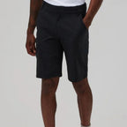 A person wearing dark charcoal cargo shorts with a white t-shirt partially visible, shown from the waist down against a light gray studio background.
