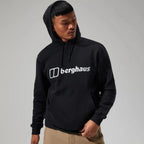 Berghaus Black Logo Hoodie for men, front view on model of black pullover hoodie with drawcord hood, kangaroo pocket and Berghaus logo across the chest, part of the Black Logo Hoodie, Tee & Pant Tracksuit