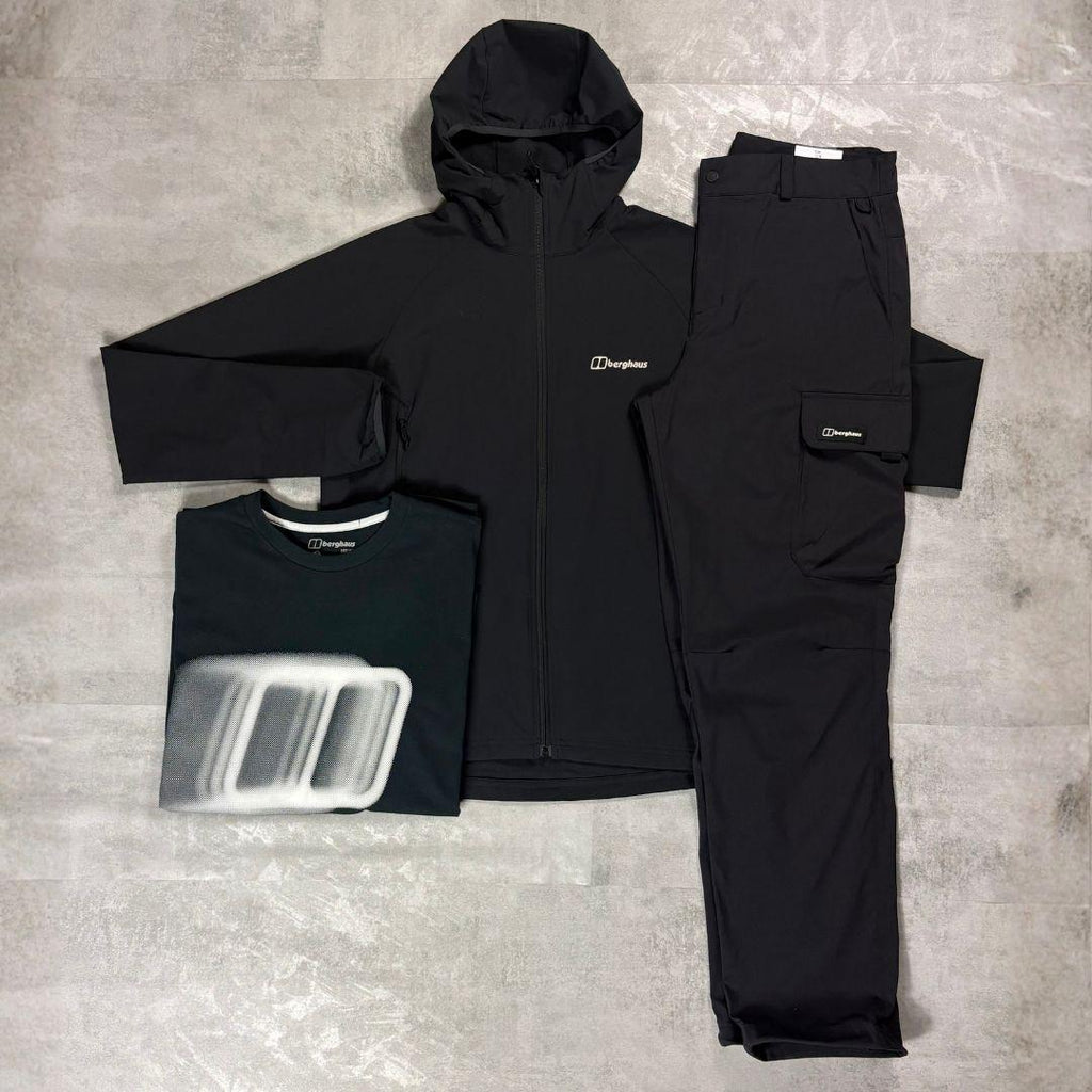 Berghaus Black Skelbo Tracksuit & Blockmorph Tee Tri-Set for men, flat lay on a grey concrete surface of the black hooded jacket, black Blockmorph graphic tee and black trousers with a thigh cargo pocket
