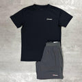 A two-piece athletic set from Berghaus, featuring a black short-sleeve performance t-shirt and dark gray shorts, laid flat on a textured gray concrete surface.