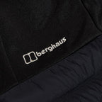 Berghaus Black Vaskye Hooded Hybrid Jacket for men, close-up of the Berghaus logo on the chest where the quilted panel meets the soft sleeve fabric