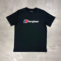 A black short-sleeve crewneck t-shirt featuring the Berghaus logo printed on the chest, laid flat on a textured gray concrete surface.