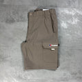 A pair of folded beige cargo shorts with an elastic waistband, laid flat on a textured gray concrete surface. The shorts feature a cargo pocket on the left leg with a white and red Berghaus logo patch.