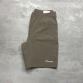 Folded brown shorts with a Berghaus logo on a gray concrete surface