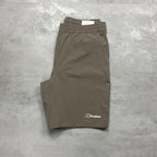 Folded brown shorts with a Berghaus logo on a gray concrete surface