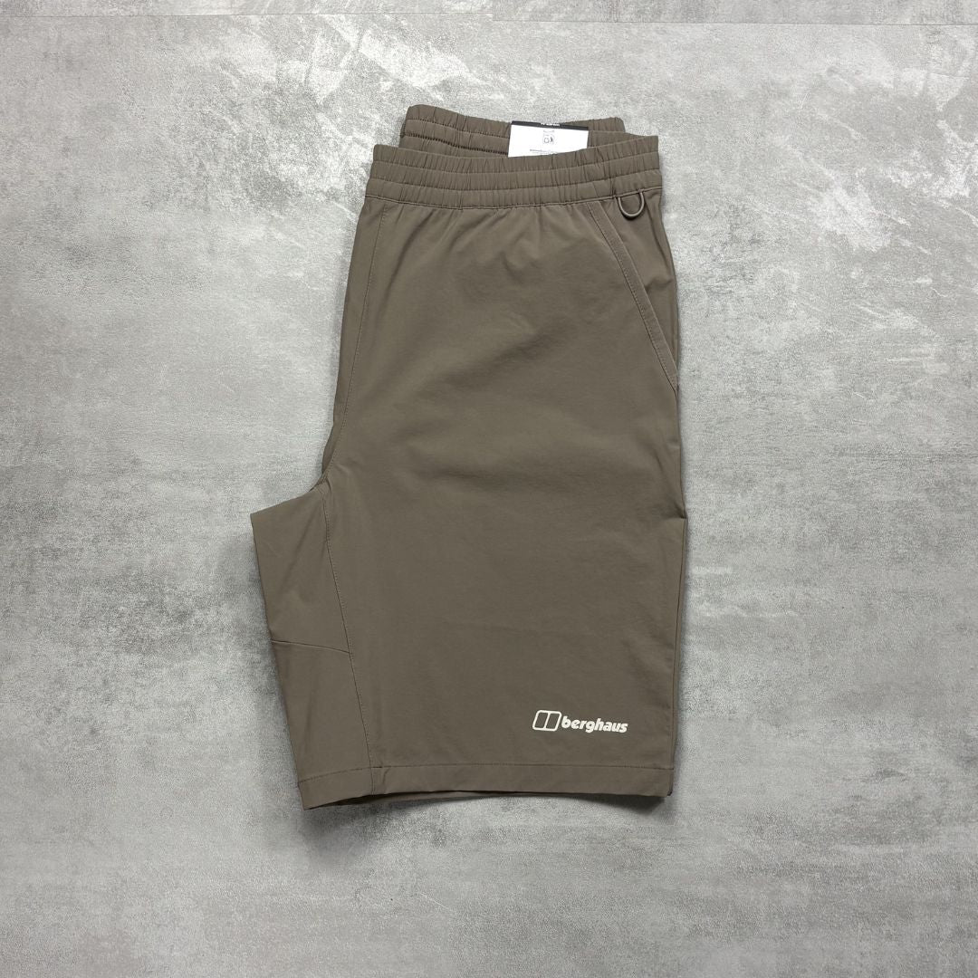 Folded brown shorts with a Berghaus logo on a gray concrete surface