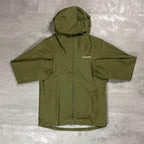 Berghaus 'Dark Green' Deluge Pro 3.0 Jacket for men, flat lay on a grey concrete surface of the dark green waterproof hooded jacket with full-zip front, zipped hand pockets and Berghaus logo on the chest
