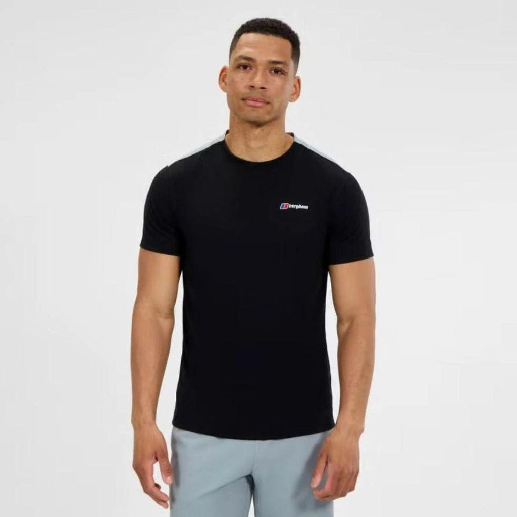 A man wearing a black short-sleeve athletic t-shirt with a small white and red Berghaus logo on the left chest, paired with light gray shorts, against a plain light gray background.