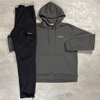 Berghaus 'Dark Grey' Logo Zip-Up Hoodie & Cargo Pant Tracksuit for men, flat lay on a grey concrete surface of the dark grey full-zip hoodie with matching black cargo pant