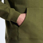 Close-up of a person wearing an olive green hoodie with a pocket.
