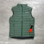 Berghaus Green Vaskye Gilet for men, flat lay on a grey concrete surface of the green quilted gilet with full-zip front and chest logo