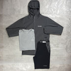 Gray and black hoodie, t-shirt, and pants with Berghaus logo on a textured gray surface