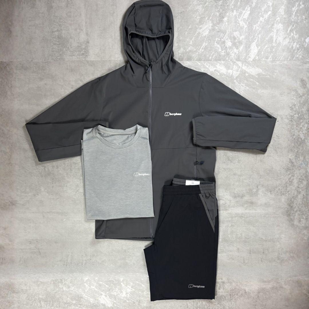 Gray and black hoodie, t-shirt, and pants with Berghaus logo on a textured gray surface