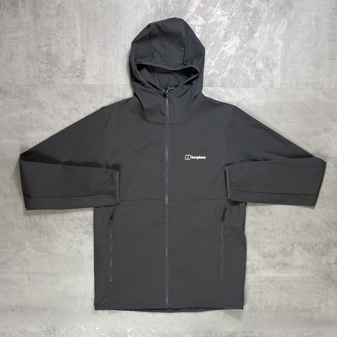 a Berghaus Grey windrunner jacket laid flat on a grey concrete background.